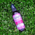 Brown bottle of Waft Rose Air Freshener with pink label on green leaf background