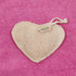 Heart-shaped LoofCo Bath-Time exfoliating pad with a brand tag on a pink textured background