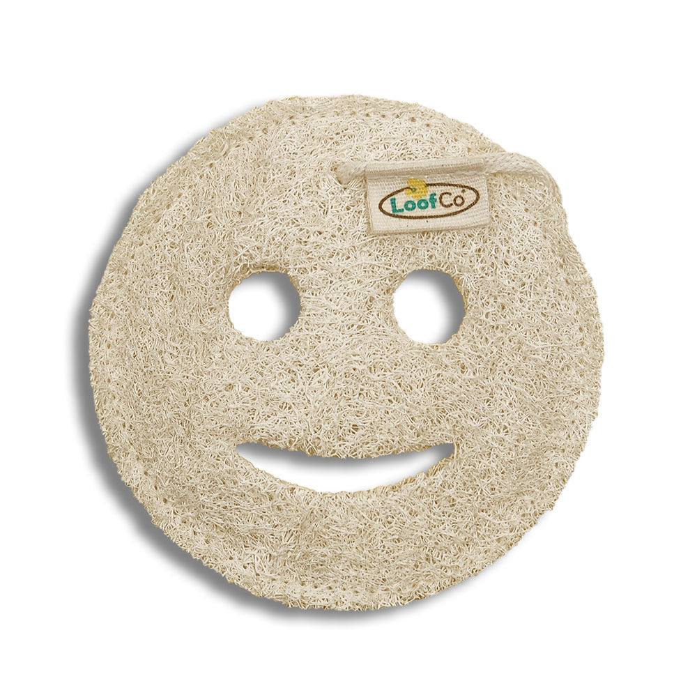Round, beige loofah with a smiley face design on a white background