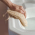 Hand holding a LoofCo bathroom Cleaning Pad loofah sponge over a white sink