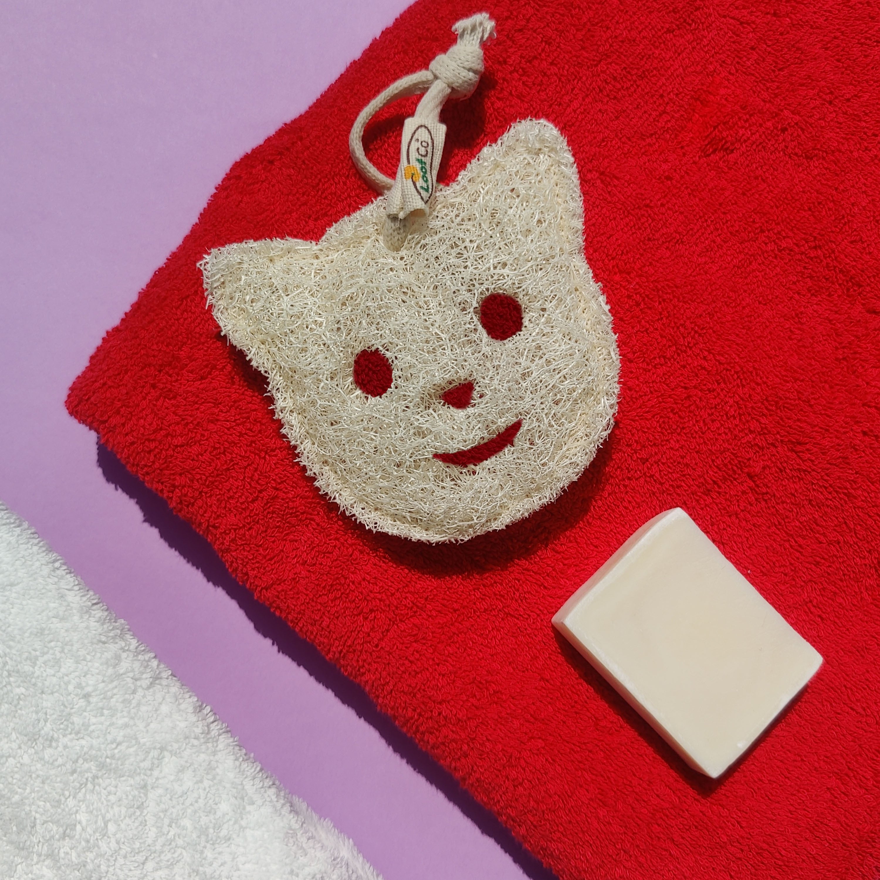 Cat-shaped sponge with a bar of soap on a red towel