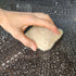 Hand holding a LoofCo Cleaning Pad loofah sponge over a soapy surface