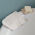 White LoofCo Cleansing Mitt and bar of soap on a white bath edge with a gray background