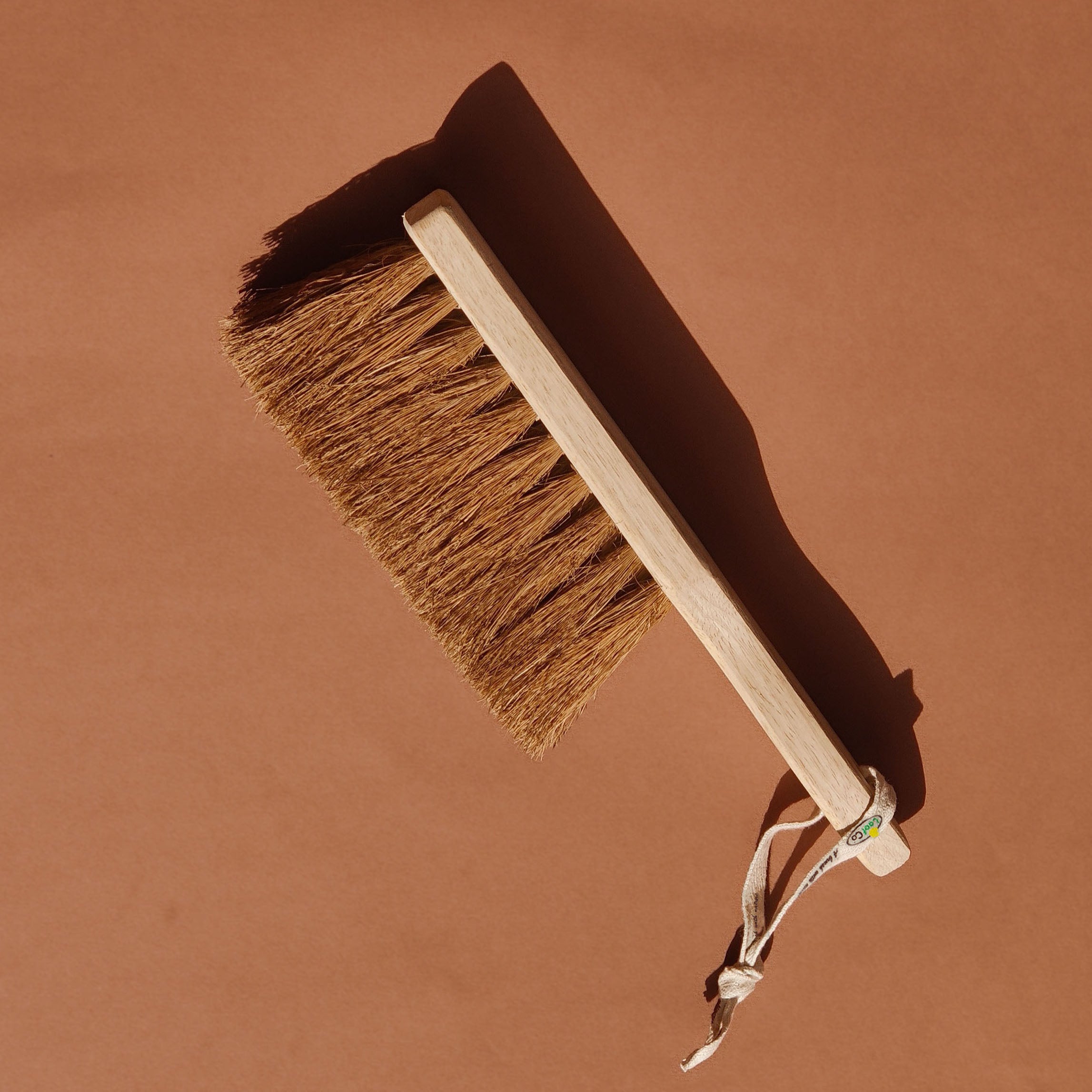 LoofCo Dust brush with wooden handle and coir bristles on a brown background
