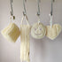 Set of natural sponges and scrubbers hanging on a rack against a neutral background