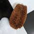 LoofCo Scrubbing Brush on a white surface with a black object and soapy water.