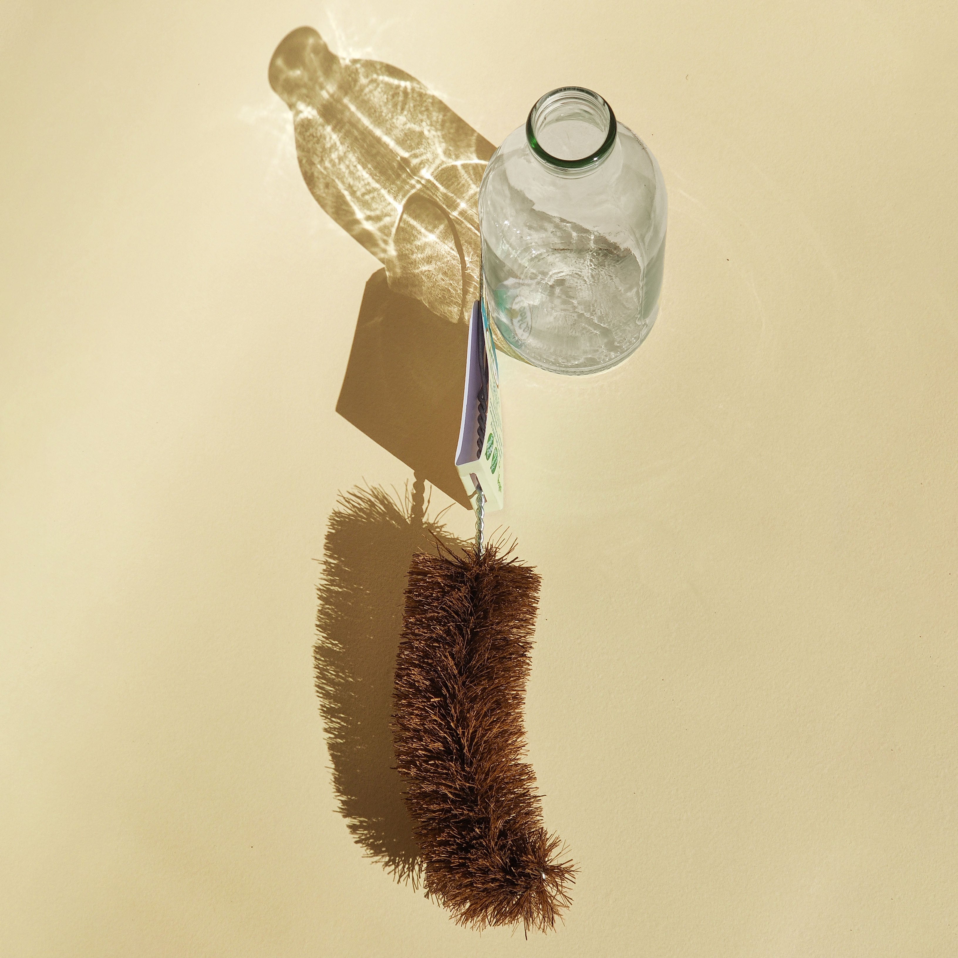 Milk Bottle brush cleaning tool with a glass milk bottle on a beige background